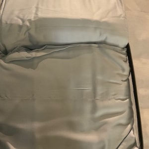 May include: A light blue, zippered storage bag with a soft, silky fabric lining. The bag is folded open, revealing the fabric lining.