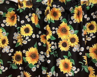 Könnte beinhalten: Schwarze Gardine mit Sonnenblumen- und Gänseblümchenmuster. Die Gardine hat einen gekräuselten Saum.