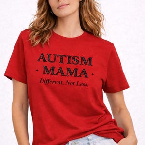 Könnte beinhalten: Rotes T-Shirt mit dem schwarzen Schriftzug "AUTISM MAMA" und dem Satz "Different, Not Less." darunter. Das T-Shirt besteht aus einem weichen Material.