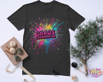 以下が含まれることがあります： カラフルなペイントスプラッターデザインの黒いTシャツ。「CHAOS COORDINATOR」の文字が鮮やかでマルチカラーのフォントでプリントされています。デザインには、ピンク、青、黄色、緑の飛沫が含まれています。