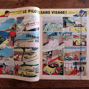 May include: Open comic book pages featuring colorful illustrations of a car racing story. The comic panels depict cars, people, and action scenes with speech bubbles. The title reads "LE PILOTES SANS VISAGE!"