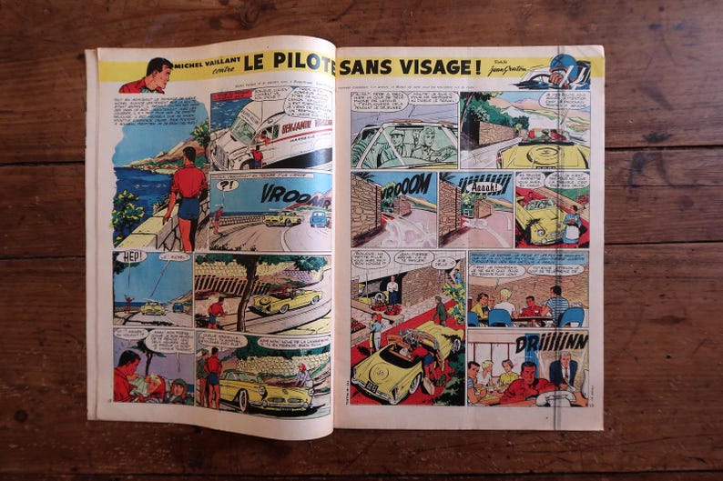 May include: Open comic book pages featuring colorful illustrations of a car racing story. The comic panels depict cars, people, and action scenes with speech bubbles. The title reads "LE PILOTES SANS VISAGE!"