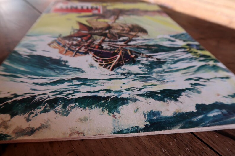 May include: A vintage illustration of a tall ship sailing through turbulent ocean waves. The artwork features a detailed depiction of the ship with its sails billowing, set against a backdrop of churning turquoise water and a yellow sky.