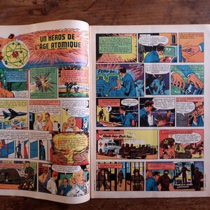 May include: Open comic book pages featuring colorful panels from a vintage comic. The title "UN HEROS DE L'AGE ATOMIQUE" is visible. The panels depict scenes with people, explosions, and a jet plane, all in a retro style.