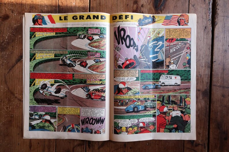May include: Open vintage comic book pages featuring a race car theme. The comic book has colorful illustrations of race cars on a track, with text bubbles and action words. The title "LE GRAND D&Eacute;FI" is visible.