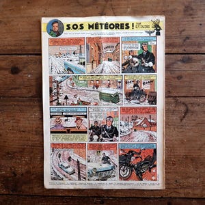 Peut inclure: Une page de bande dessin&eacute;e vintage intitul&eacute;e S.O.S. METEORES par E.P. Jacobs, compos&eacute;e d'une grille de vignettes color&eacute;es illustrant des sc&egrave;nes enneig&eacute;es, des v&eacute;hicules et des personnages en action, avec des bulles de texte en fran&ccedil;ais.