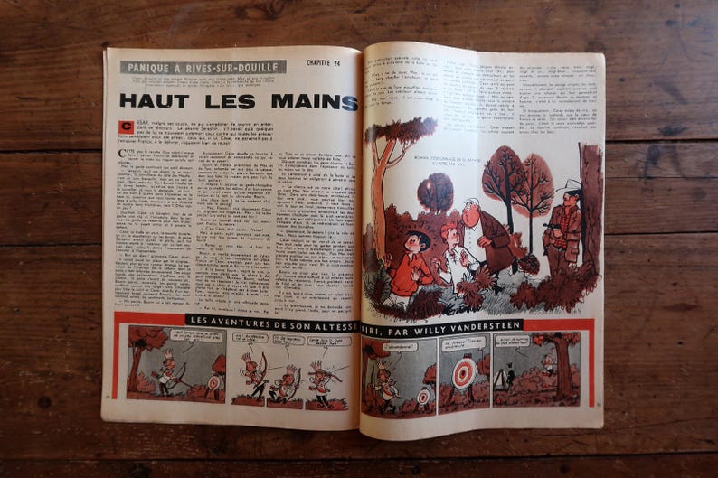Puede incluir: P&aacute;gina doble de c&oacute;mic vintage abierta, con texto e ilustraciones en franc&eacute;s. El t&iacute;tulo "HAUT LES MAINS" es prominente. El c&oacute;mic presenta vi&ntilde;etas coloridas que representan personajes en varias escenas, sobre un fondo de madera r&uacute;stica.