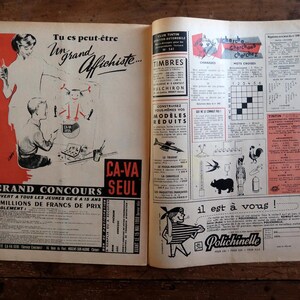 May include: Open vintage magazine pages with illustrations and text in French. One page features a contest advertisement with figures and text, while the other has various ads, including stamps and a crossword puzzle. The pages are on a wooden surface.