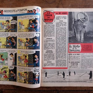 May include: Open vintage magazine spread featuring comic strips and articles. The left page displays a comic with speech bubbles. The right page has text and a photo of an elephant with a ring. The magazine is on a wooden surface.