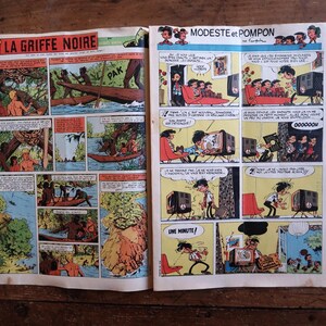Peut inclure: Une double page de bande dessin&eacute;e vintage pr&eacute;sentant deux histoires distinctes. La page de gauche est intitul&eacute;e LA GRIFFE NOIRE et illustre des sc&egrave;nes de jungle avec des pirogues. La page de droite, MODESTE et POMPON, montre des personnages.