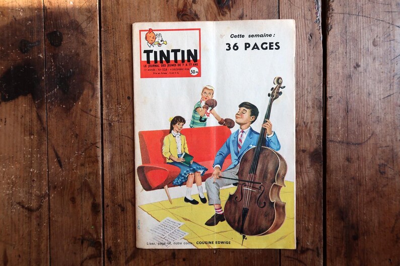 May include: Vintage "Tintin" comic book cover featuring a boy playing a cello, with other children and text. The cover has a red and white logo and text that reads "36 PAGES". The comic is on a wooden surface.
