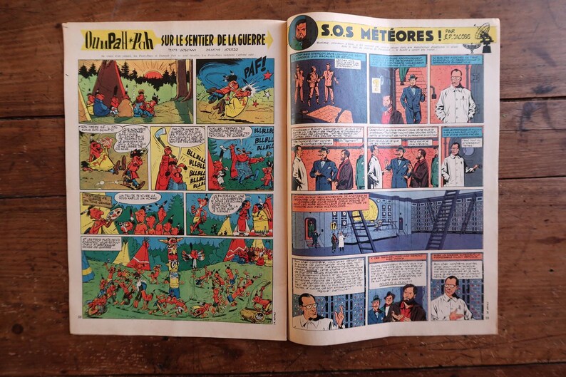 May include: Open comic book pages featuring colorful panels with illustrations and text. The left page has the title "Oumpah-Pah sur le sentier de la guerre" and comic strip panels. The right page has the title "S.O.S. M&eacute;t&eacute;ores!" with comic strip panels.