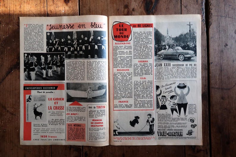 May include: Open newspaper pages with vintage articles and illustrations. Headlines include "Jeunesse en bleu" and "Le Tour du Monde." Images feature a parade, a car, and cartoon figures. The pages are on a wooden surface.