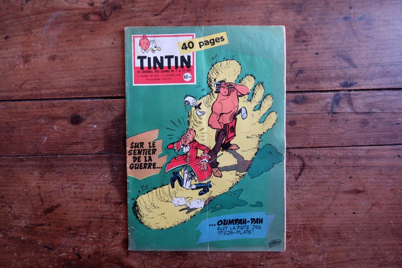 May include: A vintage Tintin comic book with a green cover featuring a large yellow footprint illustration. The cover displays the text Tintin, 40 pages, Sur le sentier de la guerre, and Oumpah-pah suit la piste des pieds-plats with cartoon characters.