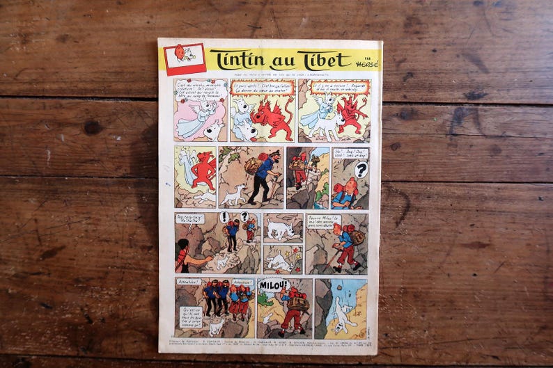 May include: A vintage comic book page titled "Tintin in Tibet" featuring colorful panels. The artwork depicts characters in various scenes, including a man with a dog, and fantastical creatures. The comic is set against a wooden background.