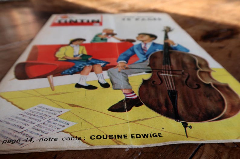 May include: Vintage comic book cover featuring a cartoon illustration. The cover shows a man playing a cello, a woman reading, and the text "TINTIN". The background is yellow with the text "COUSINE EDWIGE".