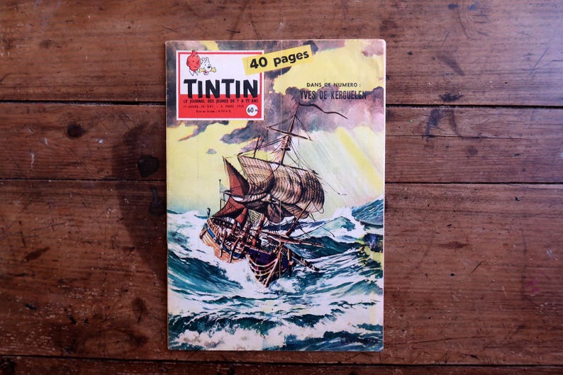 May include: A vintage comic book cover featuring a sailing ship battling rough seas. The cover has the title "TINTIN" in red and white, with the text "40 pages" in a yellow banner. The background is a wooden surface.