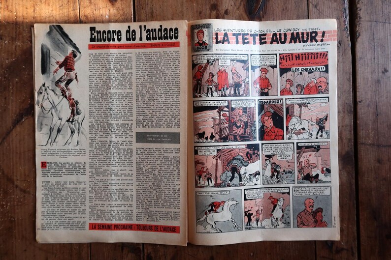 May include: Open newspaper pages featuring vintage comic strips. One page has the headline "Encore de l'audace" with an illustration of a person on a horse. The other page has the headline "LA TETE AU MUR!" with comic panels.