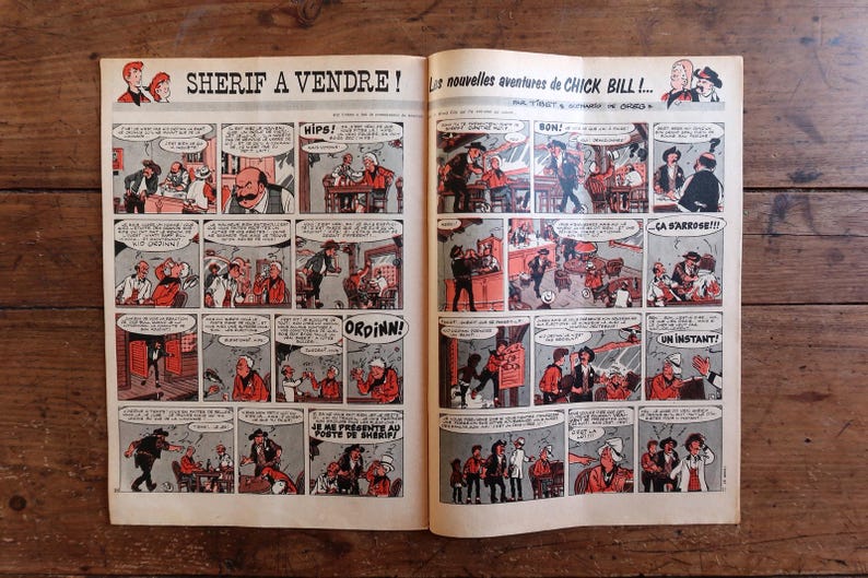 May include: Open comic book pages with a vintage Western theme. The title "SHERIF A VENDRE!" is visible, along with comic panels featuring cowboys, saloons, and speech bubbles. The comic is in black, white, and red.