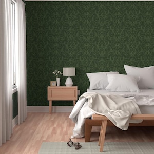 May include: A bedroom with a green damask patterned wallpaper, a wooden bench, and a bed with white bedding. A small wooden nightstand with a lamp and a vase of flowers sits next to the bed. The room has a light wood floor and a window with white curtains.