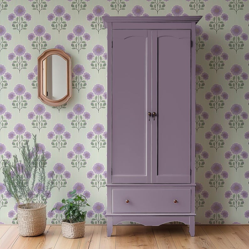 May include: A tall, solid purple wooden wardrobe featuring two vertical doors with dark metal knobs and a single wide drawer at the base with two small round knobs. The wardrobe stands on four short legs and has a smooth, matte finish.