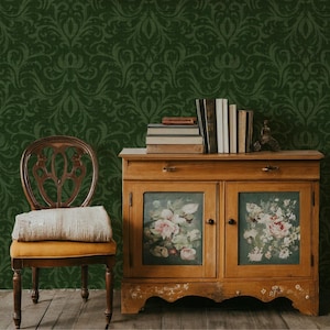May include: A vintage wooden cabinet with floral painted glass doors, topped with books and a small statue. A wooden chair with a yellow cushion and a blanket sits in front of a dark green patterned wall. The scene evokes a classic, antique aesthetic.