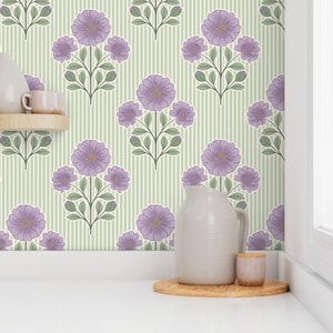 May include: Wallpaper featuring a repeating pattern of purple flowers with green leaves on a light green background with thin vertical white stripes. A light gray pitcher and a small cylindrical container sit on a wooden base.