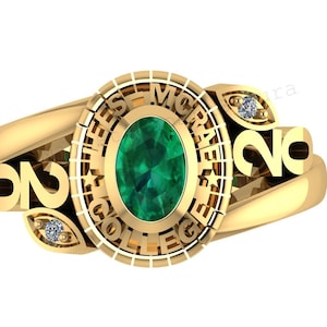 May include: A gold-colored class ring with a large oval emerald-green stone at the center. The ring features the words "HEES MORALE COLLEGE" and the year "2020". Small diamond accents are set on either side of the ring.
