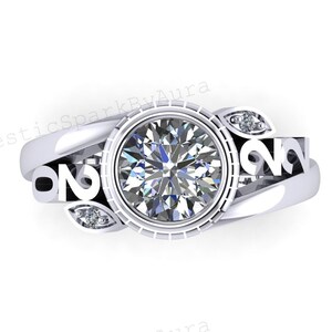 May include: A silver ring with a large, round, clear gemstone at the centre. The ring features a decorative design with smaller accent stones and the text "ON" on the sides. The ring is set against a white background.