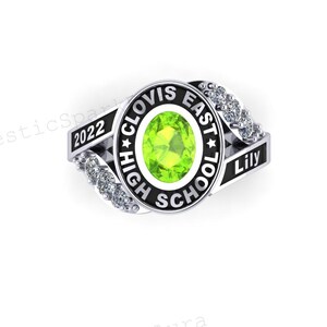 May include: Silver class ring with a central oval, light green gemstone. The ring is inscribed with "HIGH SCHOOL CLOVIS EAST" around the gemstone, and "2022" and "Lily" on the sides. Small clear stones are set along the ring's band.