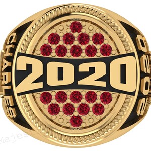 May include: Gold-toned ring with a black band featuring the year "2020" in bold numbers. The ring is adorned with red gemstones and the name "CHARLES" is inscribed on the side. A decorative rope-like border surrounds the central design.