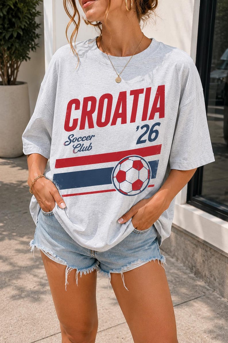 Pu&ograve; includere: Una t-shirt a maniche corte grigio chiaro con la scritta rossa CROATIA, la scritta blu Soccer Club, il numero 26 e una grafica di un pallone da calcio sopra strisce orizzontali rosse e blu. La maglietta &egrave; abbinata a pantaloncini di jeans azzurri.