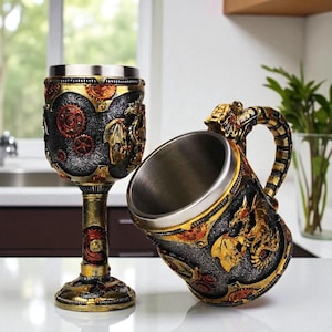 Pode incluir: Dois cálices decorativos com tema de fantasia medieval. Um é um cálice alto, o outro uma caneca com uma alça em forma de dragão. Ambos apresentam um acabamento metálico com detalhes dourados, bronze e vermelhos, e motivos de dragões e engrenagens.