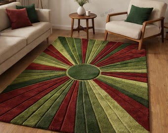 Puede incluir: Una alfombra rectangular que presenta un círculo central de color verde oscuro con patrones de rayos de sol en tonos alternos de verde oliva, verde lima y rojo intenso. La alfombra tiene una superficie texturizada y está sobre un suelo de madera.