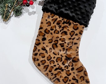 May include: A brown and black leopard print Christmas stocking with a black minky cuff.