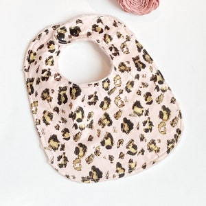 May include: A pink baby bib with a gold and black leopard print pattern.