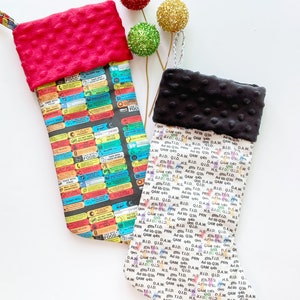 May include: Two Christmas stockings with different patterns. One stocking is red with white polka dots and the other is black with white polka dots. Both stockings have a black background with colorful text and images.