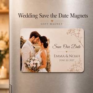 May include: A rectangular wedding save the date magnet featuring a photograph of a couple embracing, with the text Save Our Date, EMMA & NOAH, and JUNE 20, 2027, decorated with delicate floral illustrations on a light beige background.