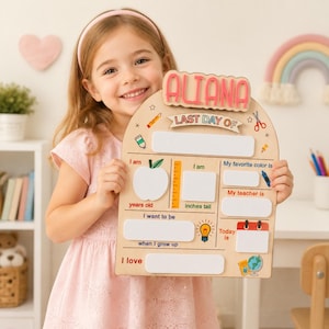Könnte beinhalten: Ein helles Holzschild mit dem Namen ALIANA in rosa Buchstaben oben. Das Schild trägt die Aufschrift LAST DAY OF und bietet weiße Leerfelder zum Ausfüllen von Details wie Alter, Größe, Lieblingsfarbe, Lehrer, Berufswunsch und Interessen.