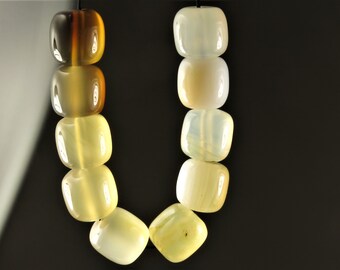 May include: A strand of light yellow and brown gemstone beads. The beads are square shaped and have a smooth, polished finish.