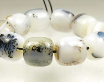 May include: A strand of white agate beads with black and brown inclusions. The beads are round and have a smooth, polished finish.