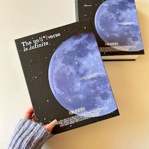 Könnte beinhalten: Zwei schwarze Boxen mit einem Himmels-Thema. Eine Box zeigt eine große blaue Mondgrafik und den Text "The un(i*)verse is infinite." Die andere Box hat ein ähnliches Design. Beide Boxen haben weiße Sternakzente.