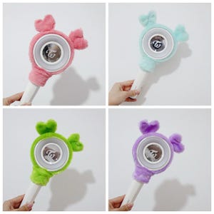 May include: Four light sticks with candy-shaped plush covers in pink, blue, green, and purple. Each has a white handle and a circular light with a logo. The covers are designed to look like sweets.