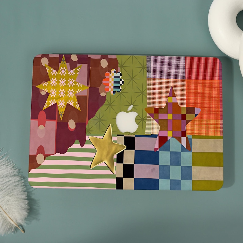 May include: A laptop skin featuring a vibrant collage of patterns including a yellow star with a geometric print, a solid gold star, a checkered star, and a small flower shape. The design incorporates stripes, plaid, and solid color blocks.