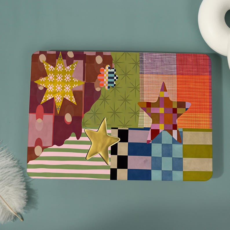May include: A rectangular laptop skin featuring a vibrant collage of patterns including green starbursts, pink and white stripes, checkered squares, and solid blocks of orange and purple, accented by three distinct star-shaped graphic overlays.