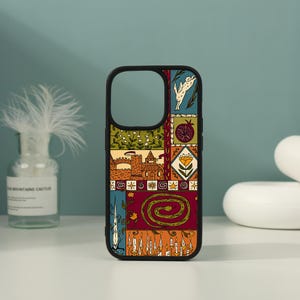 May include: A black phone case featuring a multi-paneled graphic design with illustrations of a rabbit, a pomegranate, a castle, a flower, a coiled snake, and a row of lit candles in shades of green, red, orange, yellow, and cream.