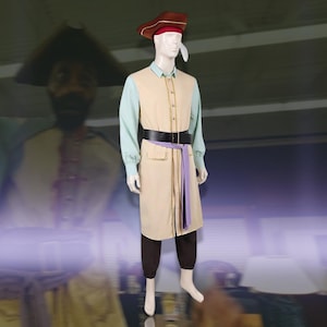 May include: A costume on a mannequin featuring a beige long vest with gold trim, a light green long-sleeved shirt, dark brown trousers, a black belt with a buckle, a purple sash, and a brown tricorn hat with a red band and a white feather.