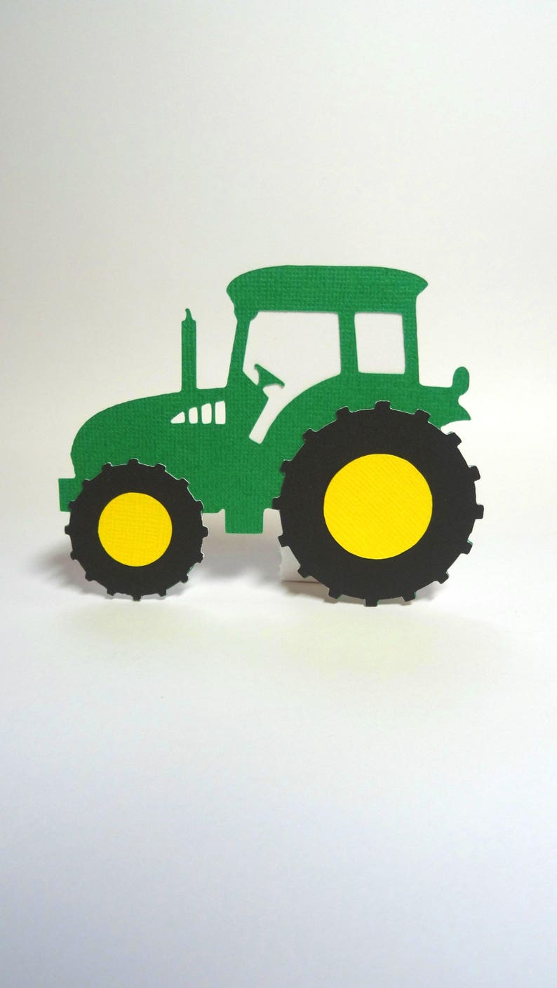 May include: Green tractor silhouette with black wheels and yellow centers. The tractor is cut out of paper and is a simple design.