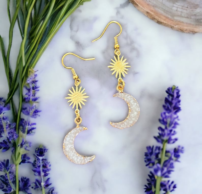 Two white crystal-like moons with a gold sun connector above them.