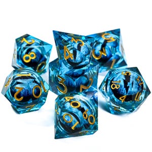 May include: A set of seven polyhedral dice with a blue and gold color scheme. The dice are transparent with a swirling blue pattern and gold numbering. Each die features a stylized eye design.